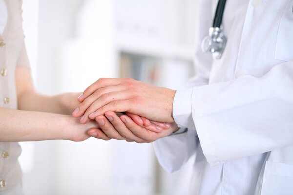 врач держит за руку пациента